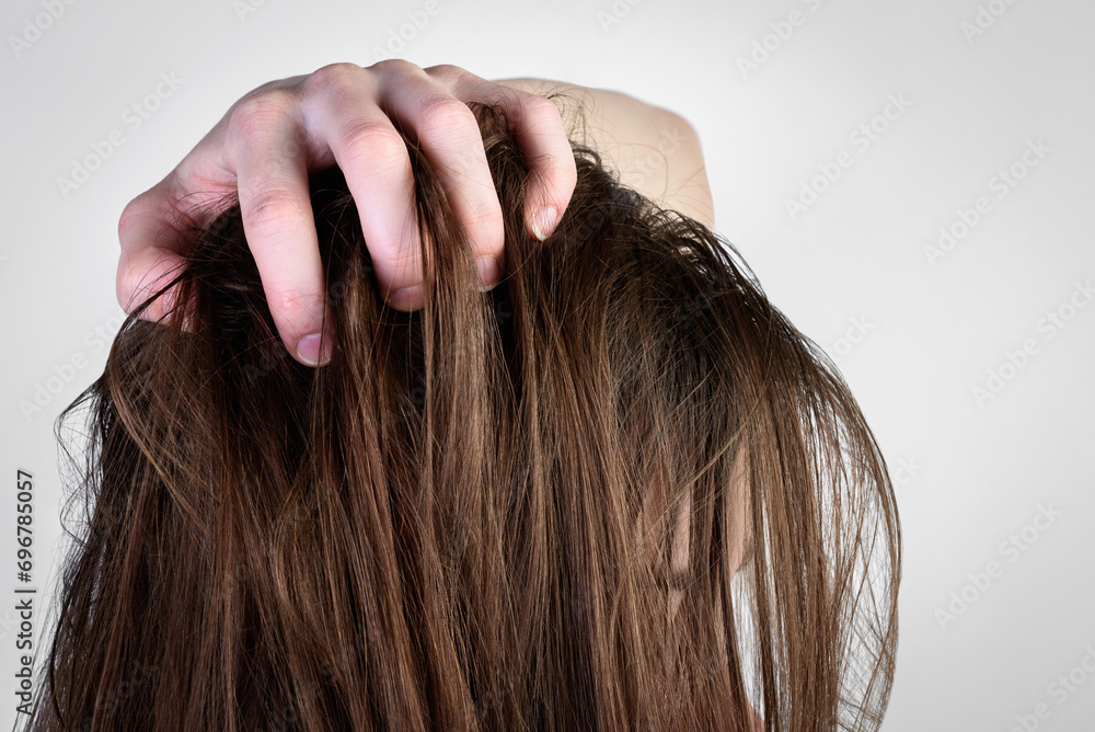 Young woman holding dirty greasy hair on gray background. Young woman holding dirty greasy hair on gray background.