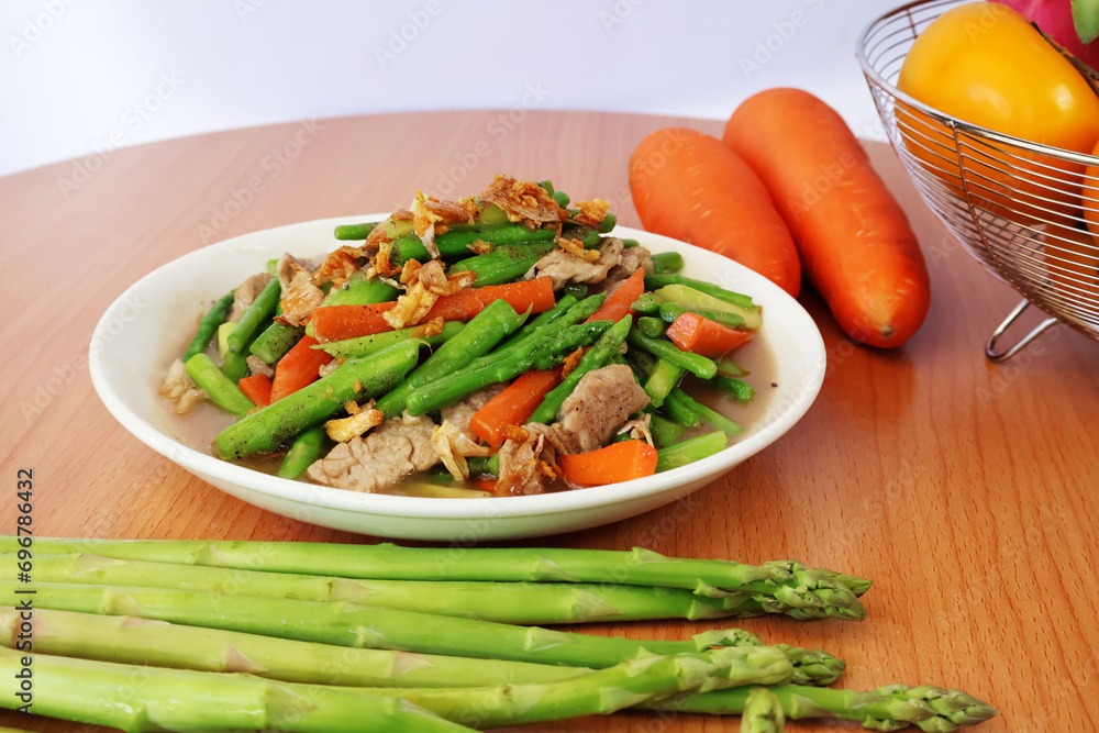 Stir-fried asparagus with pork and carrots on a wooden table
Stir-fried asparagus with pork and carrots on a wooden table