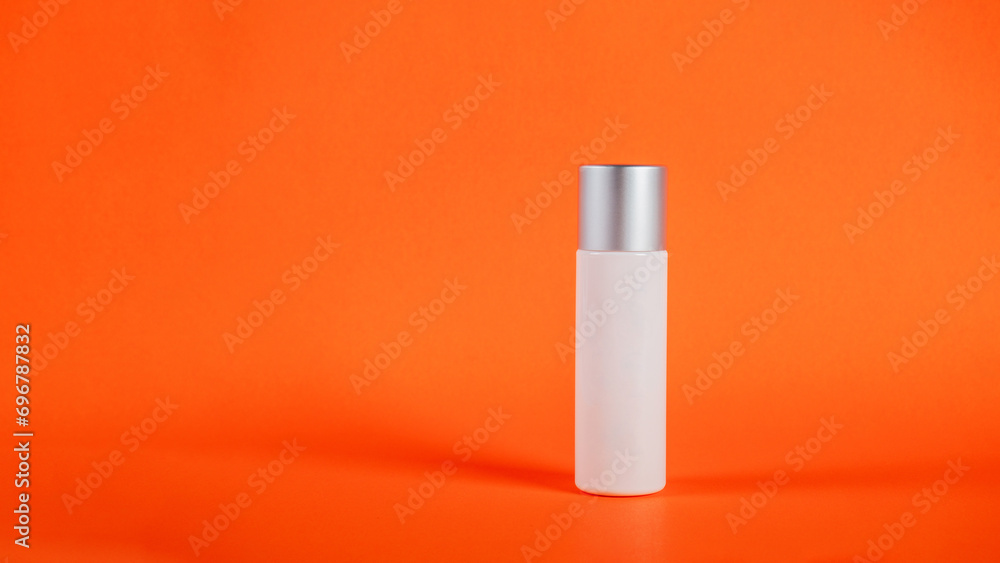Cosmetic product in tube, bottle, lotion or serum on orange background. 