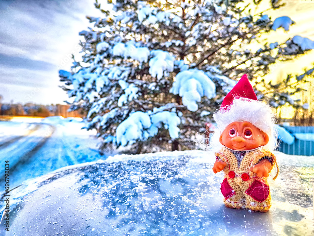 Obraz premium Cute little funny dwarf in the snow in the landscape in winter. A wizard on a snowy background. Christmas and New Year