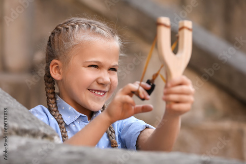 Cute little girl playing with slingshot outdoors