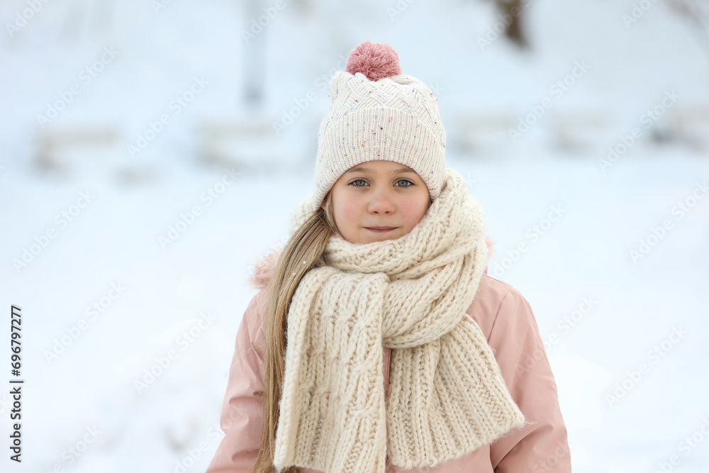 Portrait of cute little girl in snowy park on winter day