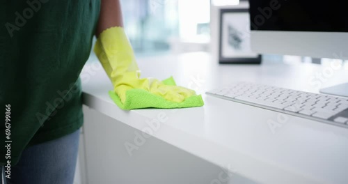 Person, cleaning office and hands as janitor, disinfecting and bacteria with safety gloves, worker and workplace. Service, hygiene and cleaner for sanitizing desk, cloth and professional cleaner photo