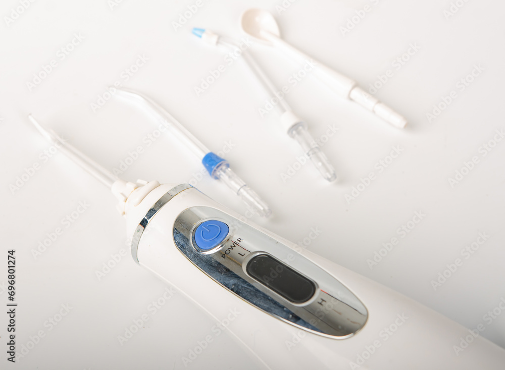 Water dental flosser with standard jet tips for teeth cleaning cordless portable rechargeable oral irrigator isolated on white background. Electronic waterproof dental flosser Water dental flosser with standard jet tips for teeth cleaning cordless portable rechargeable oral irrigator isolated on white background. Electronic waterproof dental flosser
