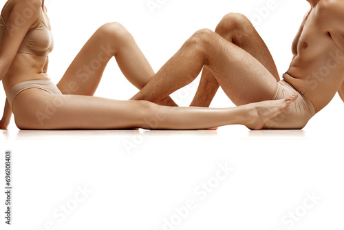 Cropped image of men's and women's bare legs against white studio background. Concept of natural beauty people, love, body care, hair removal, cosmetic products, fashion. Copy space for ad. photo