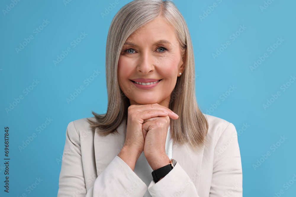 Portrait of beautiful middle aged woman on light blue background Portrait of beautiful middle aged woman on light blue background