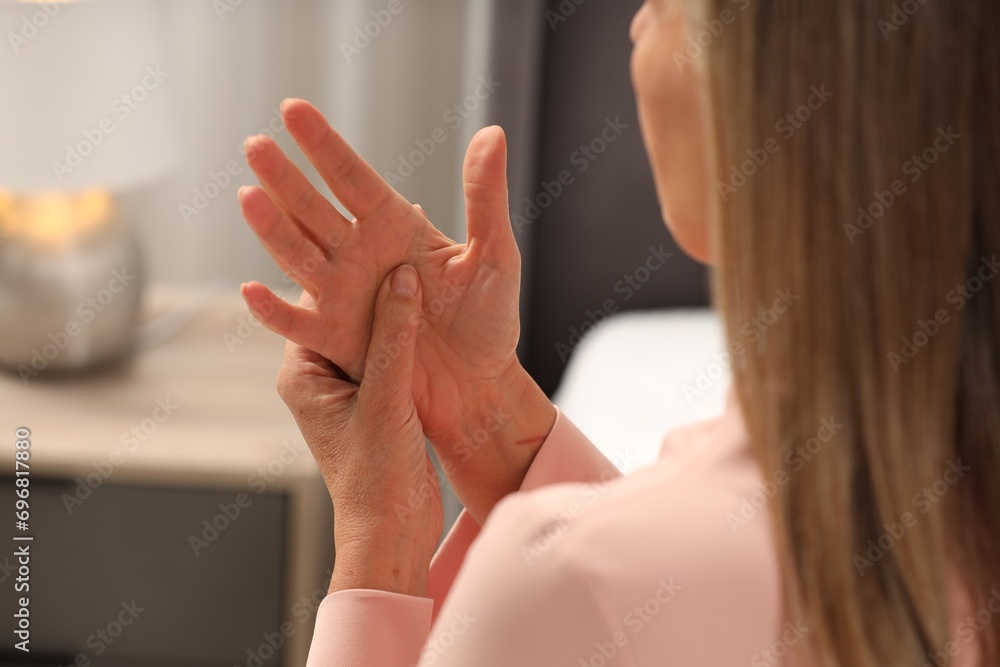 Mature woman suffering from pain in hand indoors, closeup. Rheumatism symptom Mature woman suffering from pain in hand indoors, closeup. Rheumatism symptom