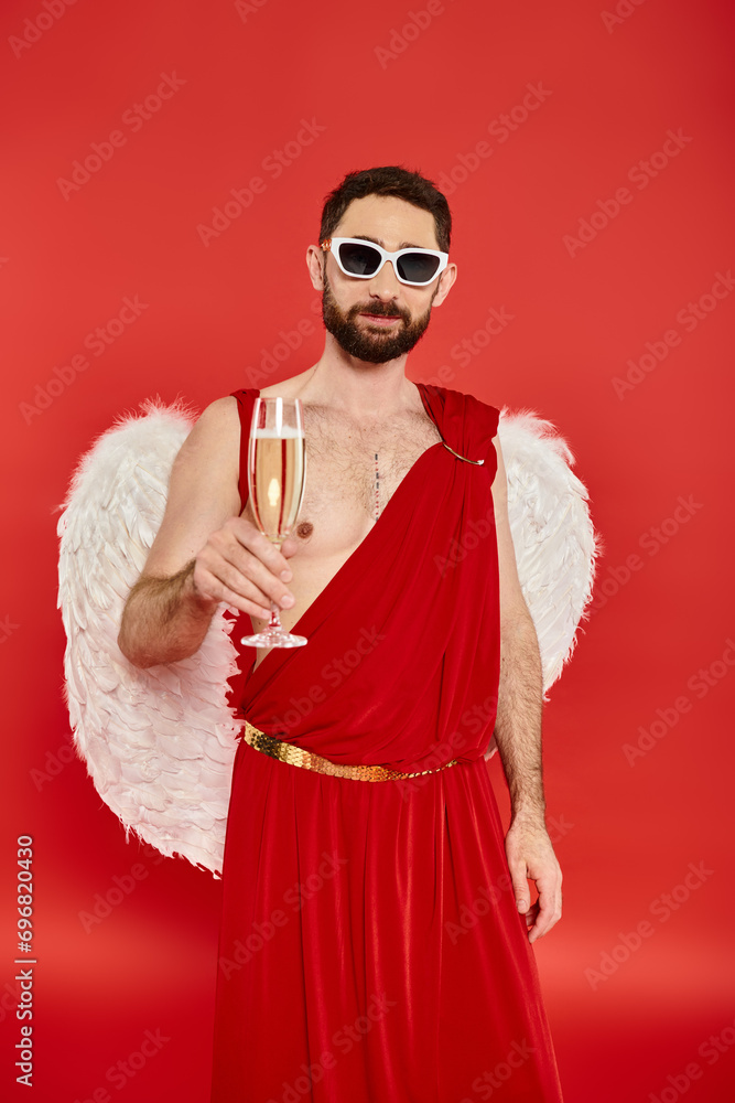 bearded man in sunglasses and  cupid costume toasting with champagne on red, Saint Valentines day