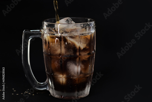 Clear glass with ice and nectar on a gray-black background. photo