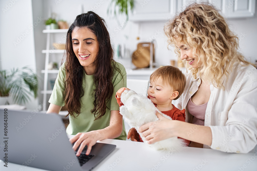 nurturing lesbian couple in homewear watching movies with their baby girl on laptop, family concept nurturing lesbian couple in homewear watching movies with their baby girl on laptop, family concept