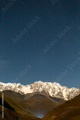 mountain valley at night, view of the snow-capped peak and starry sky