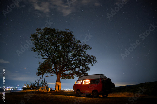 motorhome at night near a tree and starry sky