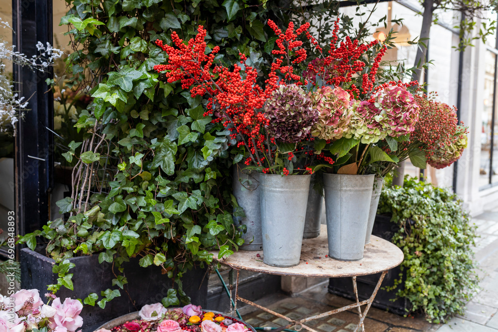 Ornamental shrubs of red and purple hydrangeas and petunias in large outdoor pots line the border of outdoor cafes and restaurants