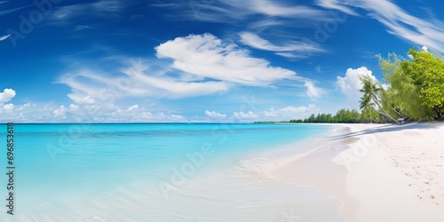 Beautiful sandy beach with white sand and rolling calm wave of turquoise ocean on Sunny day on background white clouds in blue sky.