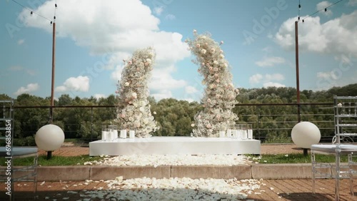 wedding arch of white rose flowers on the river bank before the wedding ceremony of the bride and groom, festive romantic decor photo