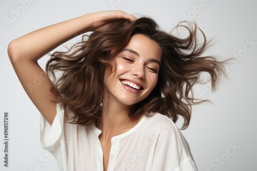 Joyful Woman Captures A Spontaneous And Happy Expression While Adjusting Her Hair In A Studio Shot