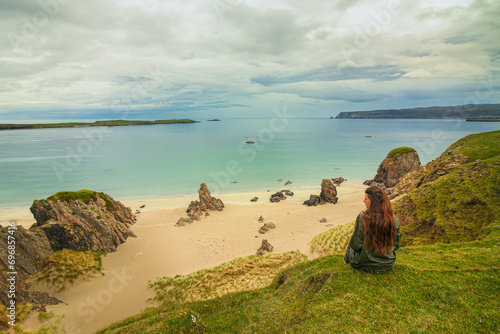 Exploring NC500's Top Beaches: A Gazing Girl on a Cliff, Embracing Scotland's Azure Sea Along the NC500 Route, Including Sango Sands, Balnakeil, and Achmelvich Beaches