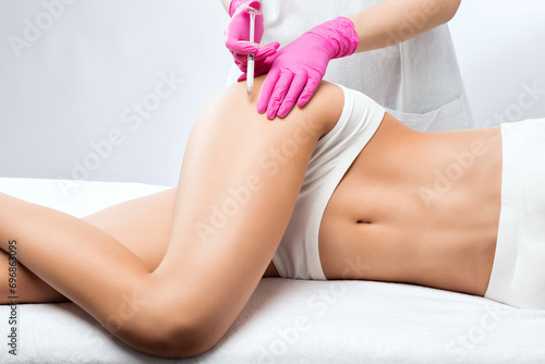 Aesthetic cosmetologist makes lipolytic injections to burn fat on the body of a woman. Female aesthetic cosmetology in a beauty salon.Cosmetology concept.