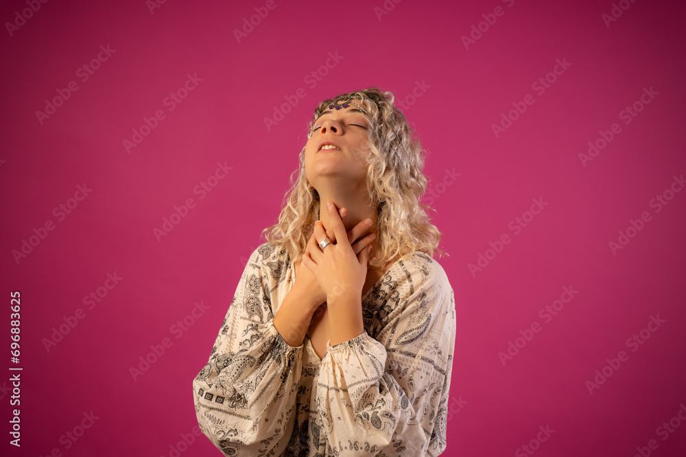 Portrait of a happy young woman in a pink jacket isolated on a pink background leaning on a high chair with a tiara on her head wearing a dress Portrait of a happy young woman in a pink jacket isolated on a pink background leaning on a high chair with a tiara on her head wearing a dress