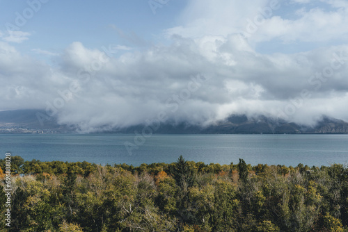 amazing beautiful top view of blue sevan lake in armenia with autumn trees below and vegetation with fluffy white clouds around photo