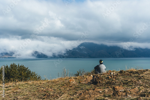 top view of man watching peacefully the sevan lake in armenia on clear but cloudy day in autumn photo