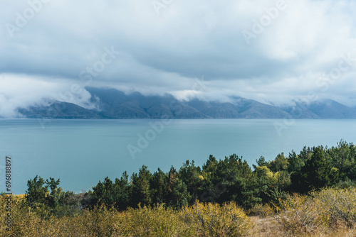 amazing beautiful top view of blue sevan lake in armenia with autumn trees below and vegetation with fluffy white clouds around photo