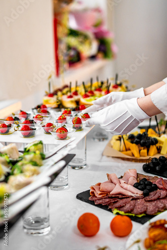 woman hands of a waiter prepare food for a buffet table in a restaurant