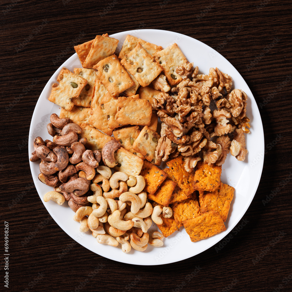 A plate with dry snacks - nuts and crackers. View from above. A plate with dry snacks - nuts and crackers. View from above.
