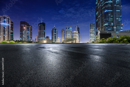 Asphalt road and modern city commercial buildings at night in Shanghai, China.