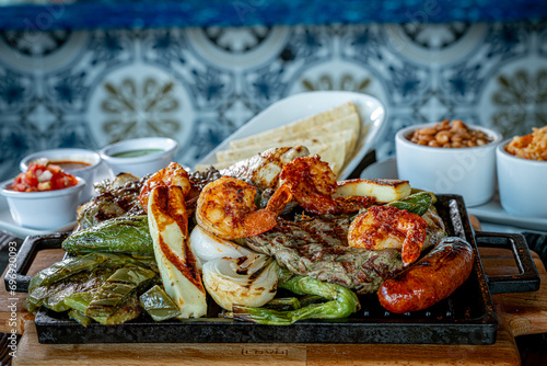 Parrillada de Sonora -Northern-style mixed grill with carne asada steak, mesquite chicken breast, chorizo links, spicy shrimp, Asadero cheese, cactus paddles, grilled onions, and chile toreado