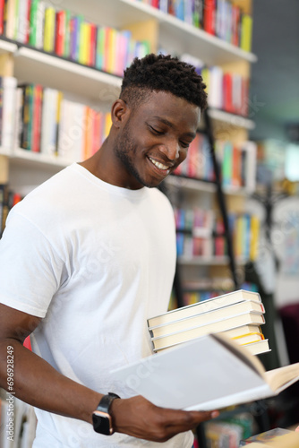 A joyful and cheerful student in the university library, surrounded by books, immersed in academic pursuits and displaying happiness.