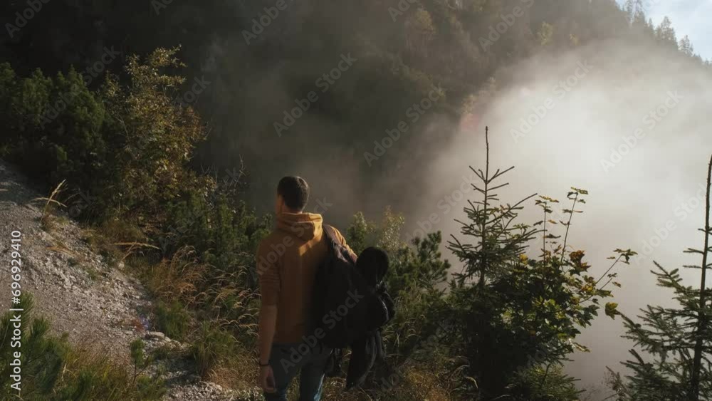 Man traveler walks through the forest to the mountains. Incredibly beautiful views in the Alpine mountains. Hiking route in the Alps mountains in autumn. Slow motion Man traveler walks through the forest to the mountains. Incredibly beautiful views in the Alpine mountains. Hiking route in the Alps mountains in autumn. Slow motion