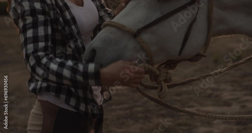 Woman, cowgirl and horse in sunset for trust, support or loyalty with companion on adventure in countryside. Face of female person or farmer touching animal saddle for love, care or ride in nature photo