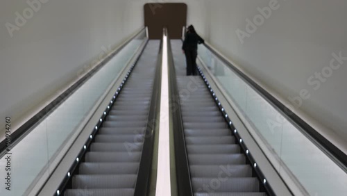 Futuristic shot of escalator in tunnel with girl going up.