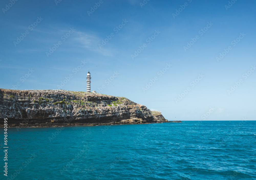 Lighthouse on top of cliffs in a blue sea in the Abrolhos archipelago
