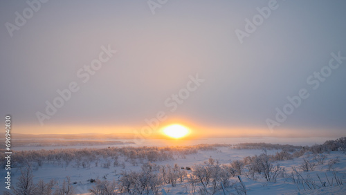 A serene winter sunrise over a snowy landscape, conveying the calmness and beauty of early morning in a cold climate