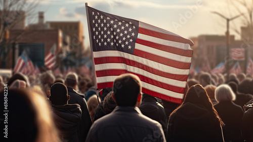 Rear view of a group of people at a parade or protest with a United States of America flag. © OleksandrZastrozhnov