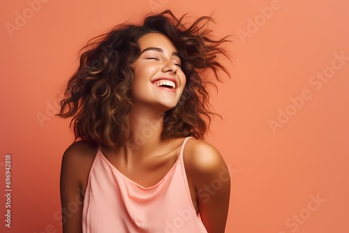 A cute and beautiful young female model with a carefree and joyful pose, radiating a spirit of freedom and adventure, against a solid light coral background. photo