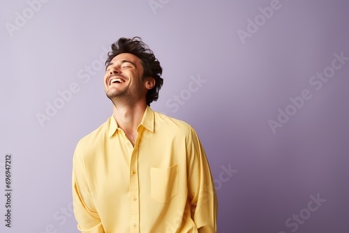 A man radiating joy in a pastel yellow shirt on a gentle lilac background.