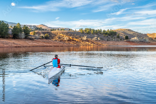 Senior male rower is rowing a coastal rowing shell - Horsetooth Reservoir in fall or winter scenery in northern Colorado.