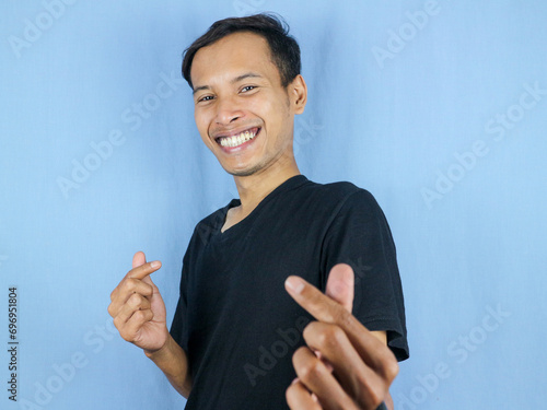 handsome asian man is making a heart shape symbol with his fingers. love and romantic concept. photo