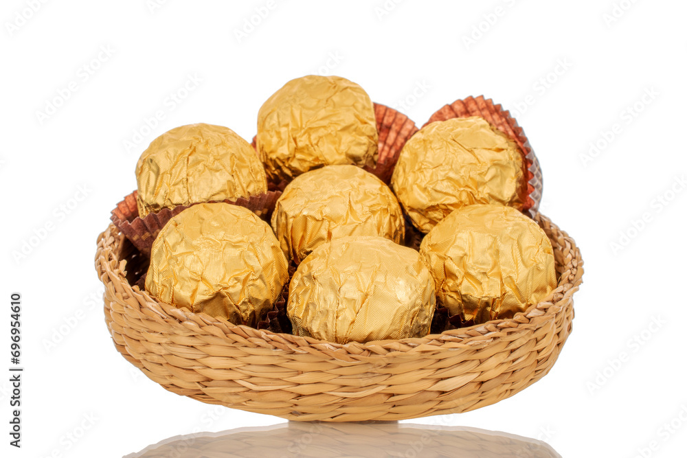 Several chocolates in a paper wrapper on a straw plate, macro, isolated on a white background. Several chocolates in a paper wrapper on a straw plate, macro, isolated on a white background.