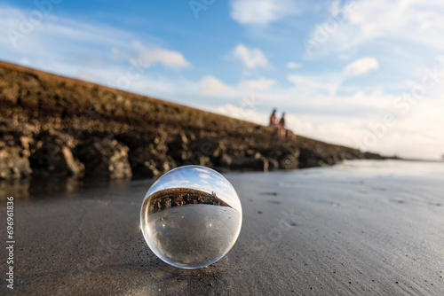 Santos city, Brazil. Crystal ball on the beach sand next to the wall of water channel nº6 reflecting the landscape. Defocused background. 