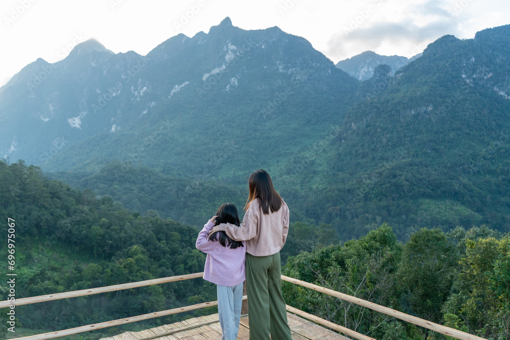 Mother and daughter standing on the mountain and enjoy the view.