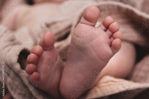 The legs of a newborn baby on a beige muslin towel. High quality photo