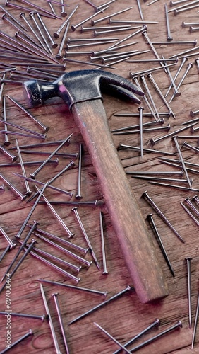 Old stained iron hammer on wooden table surrounded with nails. 3D illustration