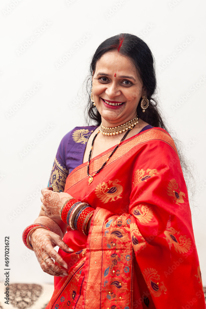 A beautiful, happy Indian woman is wearing a red saree and looking directly at the camera.