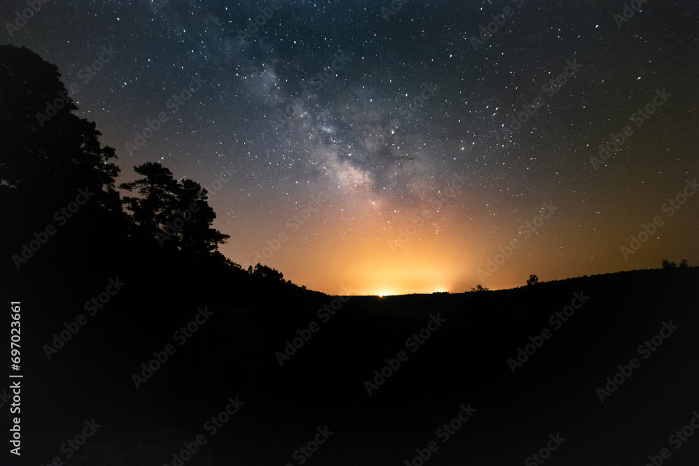 The starry sky and Milky Way above open fields and trees