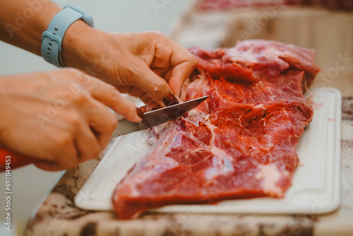 Cook preparing red meat for the barbecue. Barbecue is a delicacy made from fresh or processed meat, roasted over a fire or coals, using skewers or grills.