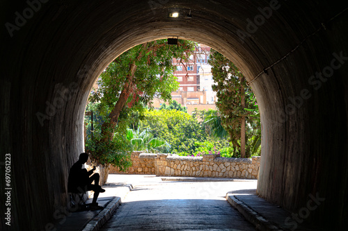 Guitar player silhouette in tunnel darkness. Street artist performing in the shadow.